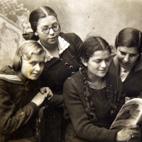 Four pupils from a state secondary school in Chełm are leaning over a book. One is looking straight ahead.
